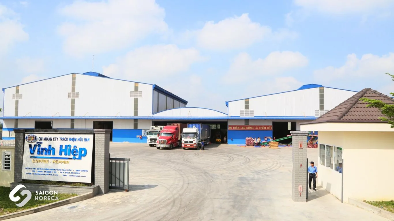 Cổng và mặt tiền nhà máy cà phê Vĩnh Hiệp với xe container đang nhận hàng
