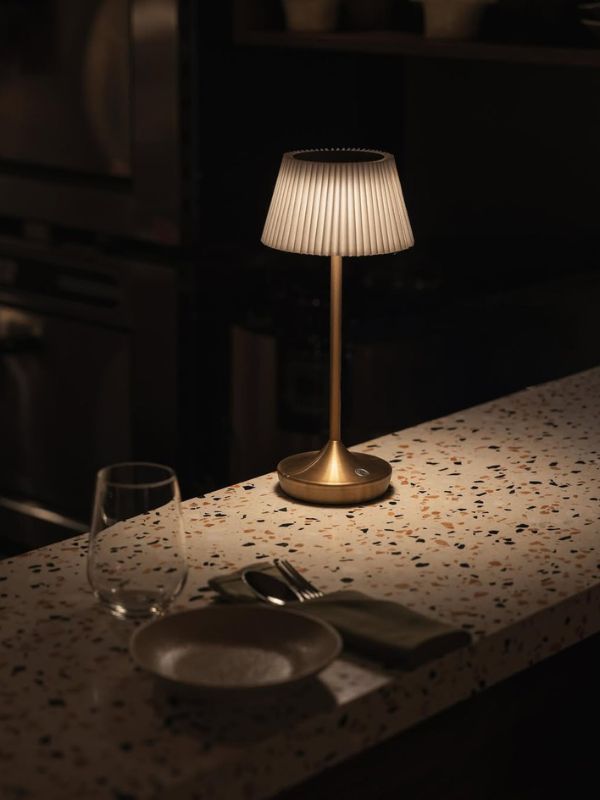 Cận cảnh mặt bàn terrazzo điểm đèn để bàn mạ vàng và bộ đồ ăn – chi tiết tạo nên không khí ấm áp