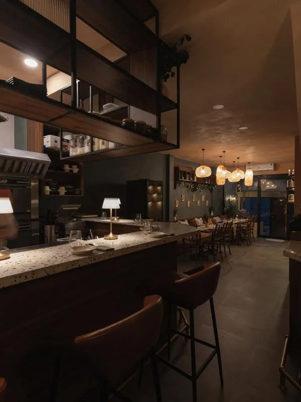 Không gian quầy bar terrazzo và khu bàn ghế ăn hòa quyện dưới ánh đèn thả mây ấm áp