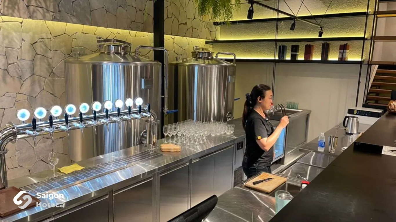 Quầy bar rót sake với bồn inox và dàn vòi rót tại Mùa Craft Sake