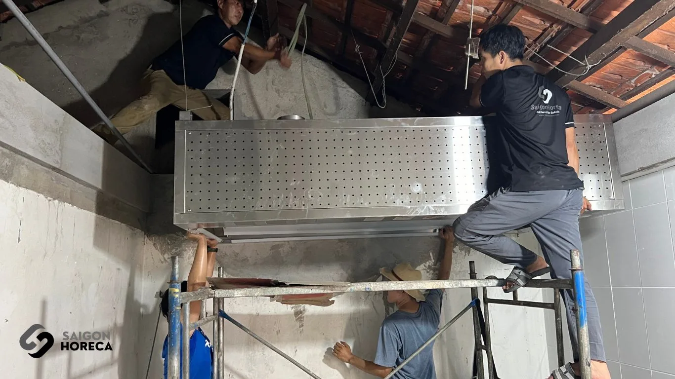 Thợ Saigon Horeca lắp đặt chụp hút khói inox dài 2m lên trần trong quá trình thi công bếp Sol Kitchen & Bar Quận 7
