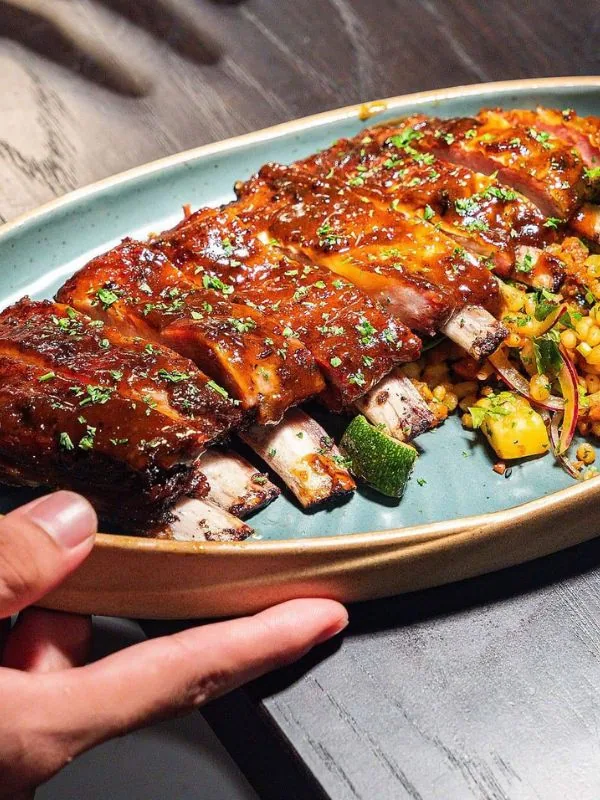 Đĩa sườn heo nướng BBQ sốt nâu đỏ ăn kèm couscous trộn rau củ tại Sol Kitchen & Bar